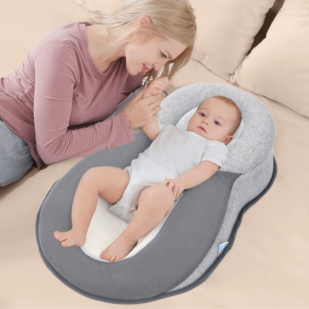 Mother smiling at baby lying in DreamNest baby bed.